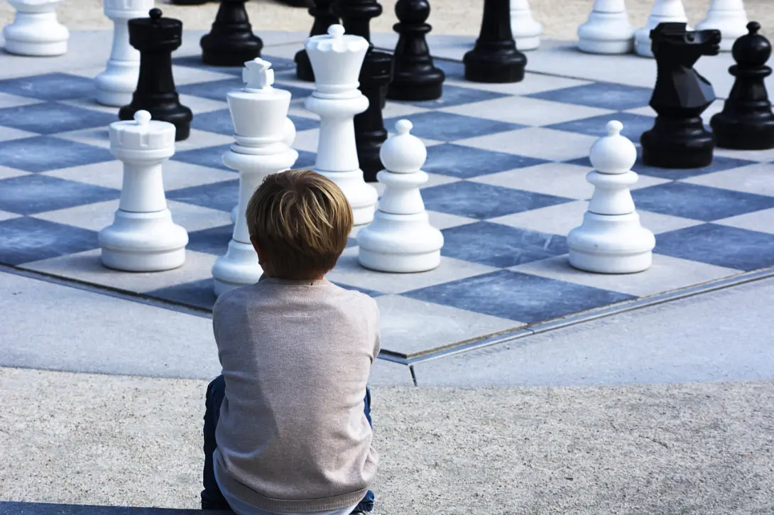 Un enfant assis devant un échiquier géant